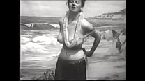 大きなメロンを持った遊び心のある女性がハワイアンの衣装を脱いでビーチで丸いお尻を見せます