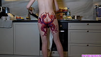 Femme au foyer nue avec un tatouage de poulpe sur le cul prépare le dîner dans la cuisine et vous ignore